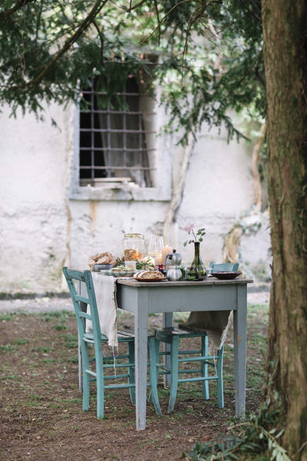 Стол в саду со свечами рядом с коттеджем — стоковое фото