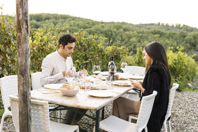 Italia, Toscana, Siena, pareja joven cenando en un viñedo - foto de stock