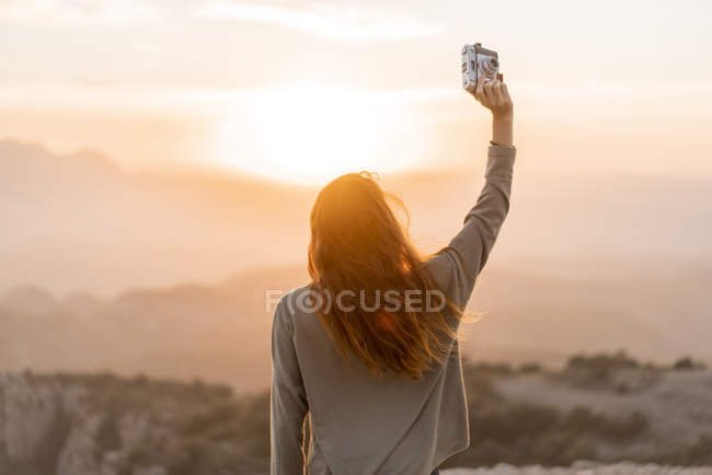 Іспанія, Барселона, природний парк Сант-Лоренц, задній вид жінки з вінтажною камерою на заході сонця — стокове фото