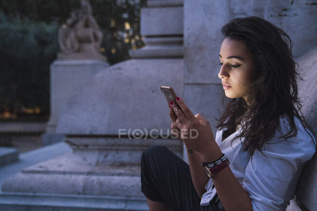Jeune femme utilisant un téléphone cellulaire au crépuscule du soir — Photo de stock
