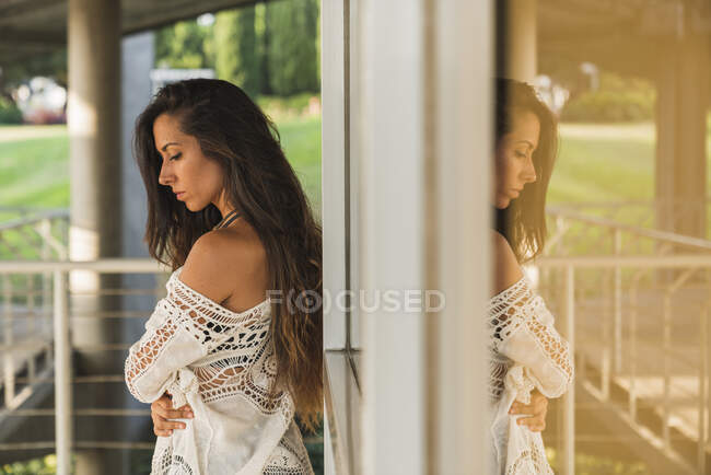Serious brunette young woman at a window outdoors — Stock Photo