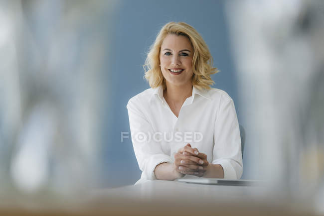 Портрет улыбающейся деловой женщины, сидящей за столом — стоковое фото