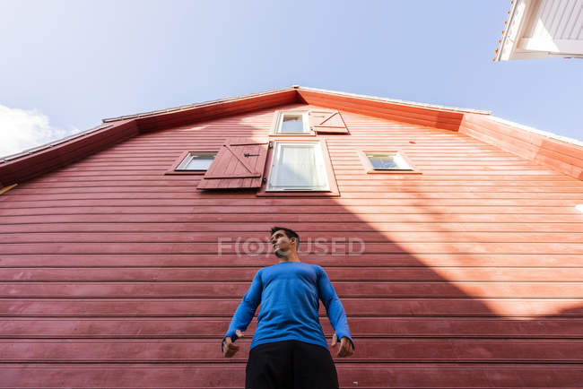 Низький кут зору спортсмена стоячи перед червоним будинком — Stock Photo