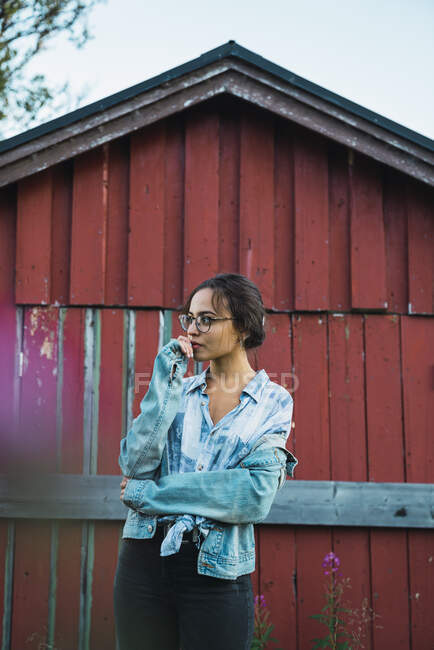 Portrait d'une jeune femme debout devant une hutte en bois rouge — Photo de stock
