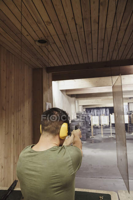 Man aiming with a pistol in an indoor shooting range — Stock Photo