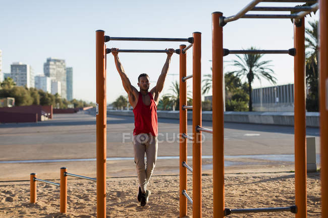 Fit man working out in climbing parcour, doing pull ups — Stock Photo
