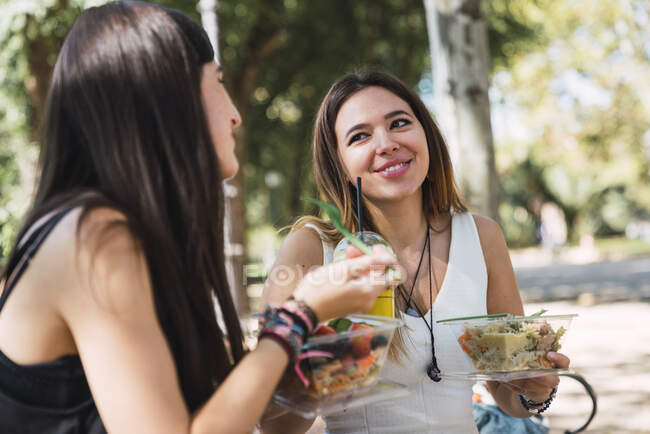 Друзья сидят в парке, едят салат — стоковое фото