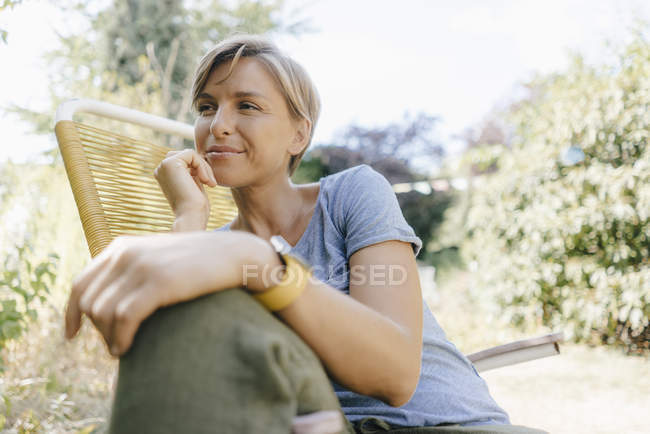Frau sitzt im Garten auf Stuhl — Stockfoto
