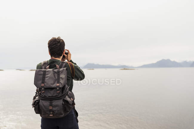 Young man taking pictures of a lake in Vesteralen Island, Lapland, Norway — Stock Photo