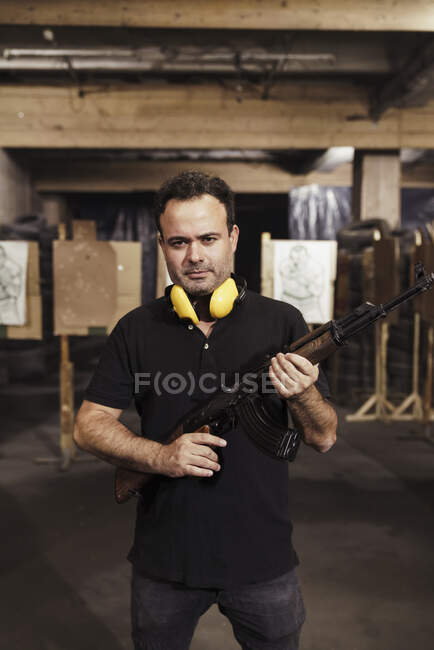 Портрет человека, держащего винтовку в помещении тира — стоковое фото