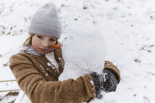 Хлопчик обіймає сніговика — стокове фото