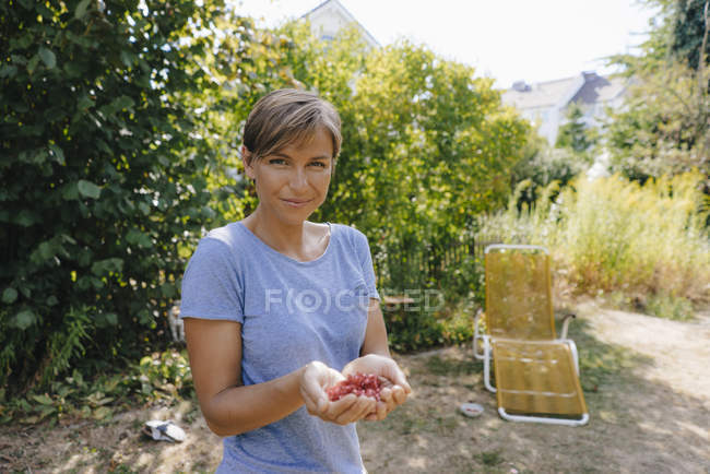 Portrait of smiling woman holding pomegranate seeds — Stock Photo