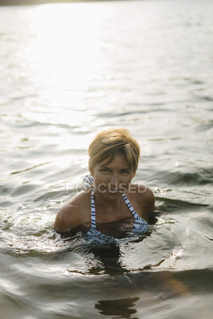 Portrait of smiling woman swimming in a lake — Stock Photo