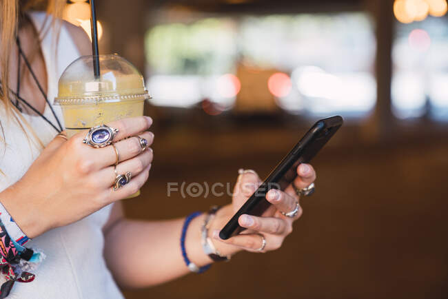 Молодая женщина с помощью смартфона и питьевого сока — стоковое фото