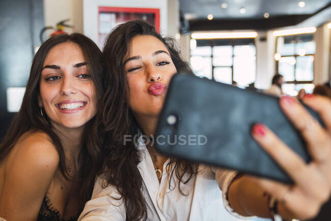 Porträt zweier Freunde, die ein Selfie mit dem Smartphone in einem Café machen und dabei Spaß haben — Stockfoto