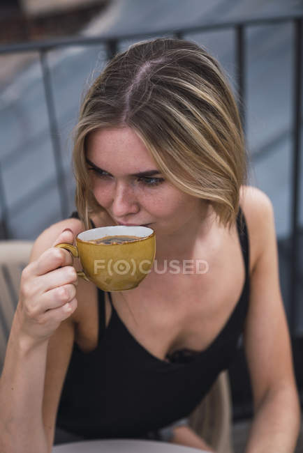 Jovem mulher bebendo xícara de café no terraço — Fotografia de Stock