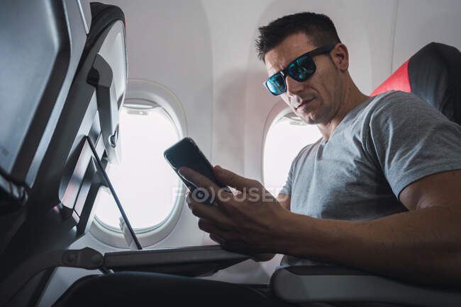 Uomo in aereo, con smartphone, cuffie — Foto stock