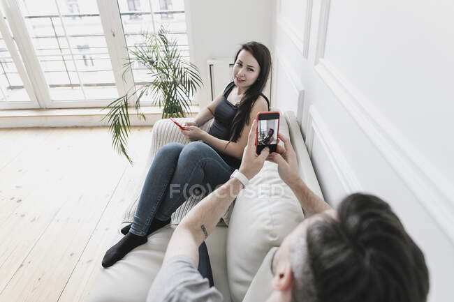 Casal sentado em casa no sofá, usando seus smartphones — Fotografia de Stock