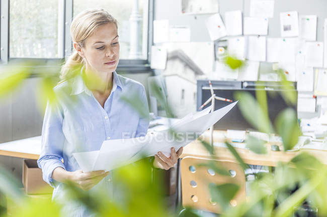 Frau im Amt arbeitet an Plan mit Windkraftmodell auf dem Tisch — Stockfoto