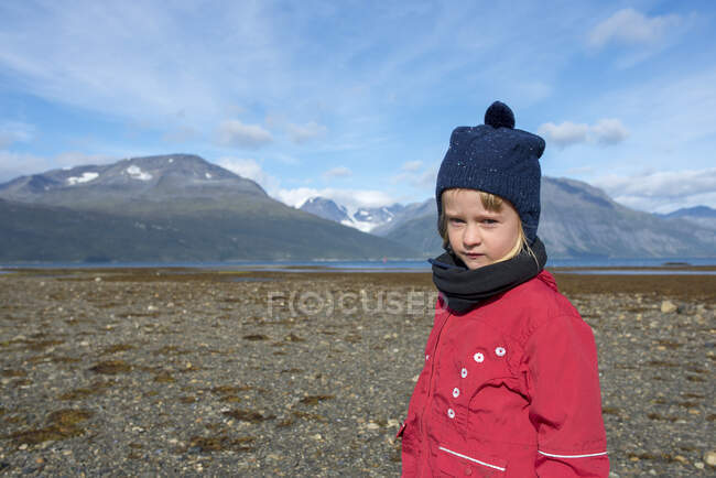 Норвегія, дівчинка в капелюсі бульбашки і червоний піджак на пляжі, фіорд Лінгена — стокове фото