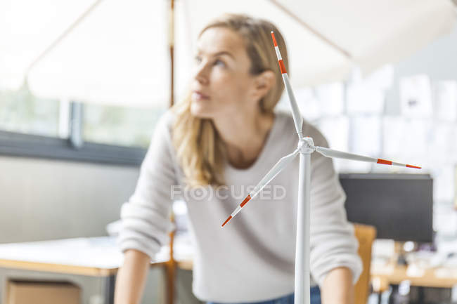 Mujer en oficina trabajando en el modelo de turbina eólica - foto de stock