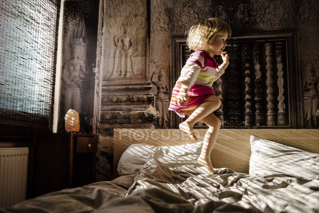 Little girl jumping on parent's bed at home having fun — Stock Photo