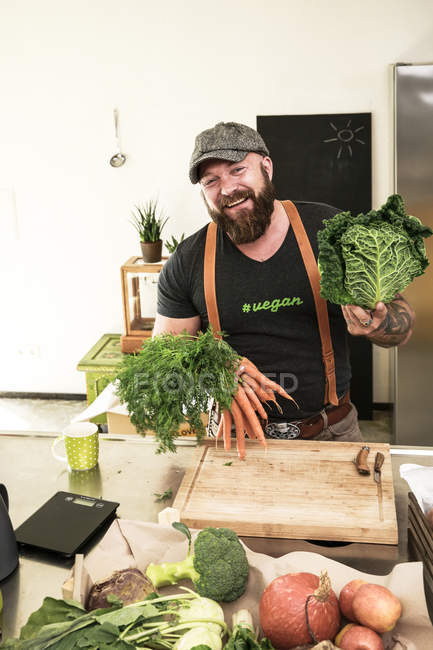 L'uomo vegano sceglie le verdure nella sua cucina — Foto stock