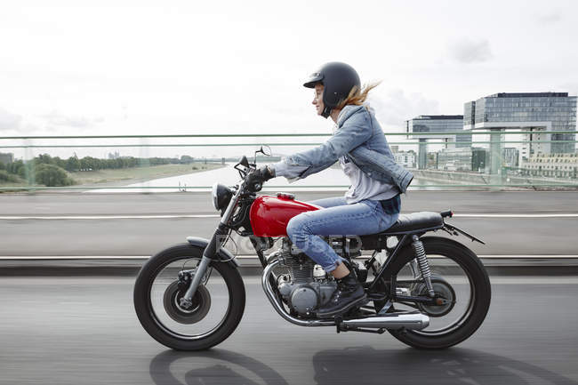 Germany, Cologne, young woman riding motorcycle on bridge — Stock Photo