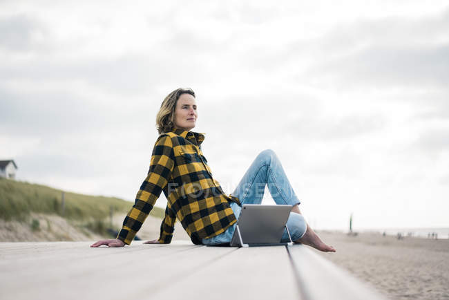 Donna matura seduta sul lungomare in spiaggia, utilizzando il computer portatile — Foto stock