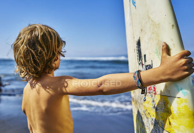 Chile, Pichilemu, chico de pie junto al mar con tabla de surf - foto de stock