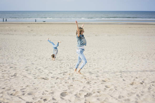 Mère et fille s'amusent, roulent sur la plage — Photo de stock
