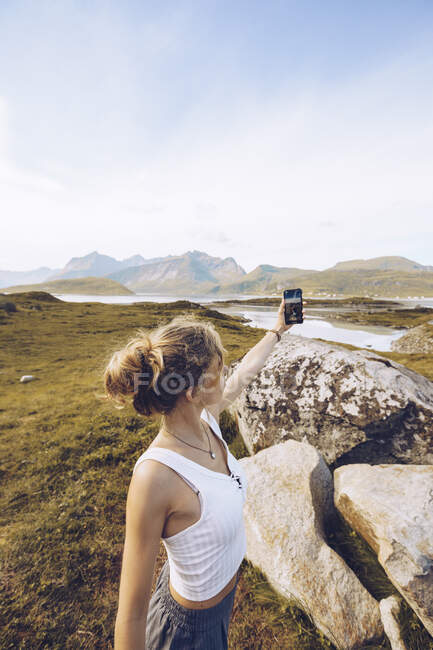 Noruega, Lofoten, jovem mulher tomando selfie com smartphone na natureza — Fotografia de Stock