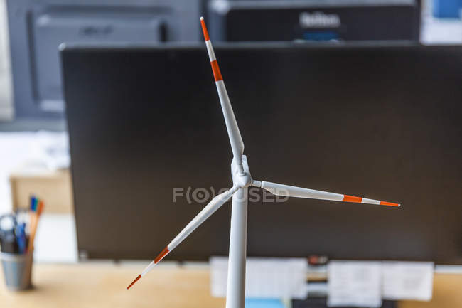 Крупный план модели ветряной турбины и настольного компьютера в офисе — стоковое фото