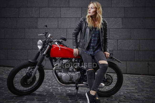 Jovem confiante com motocicleta olhando para longe — Fotografia de Stock