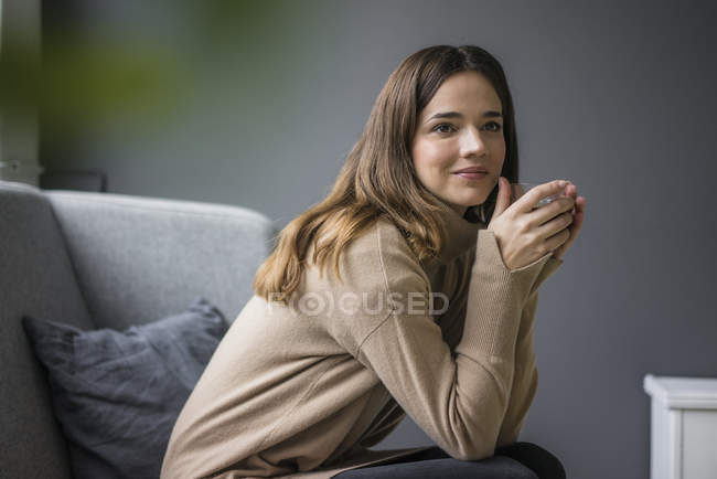 Portrait de femme souriante dégustant un verre de café à la maison — Photo de stock