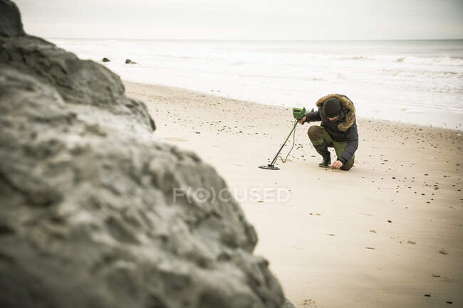 Человек с металлической трубой на песчаном пляже — стоковое фото