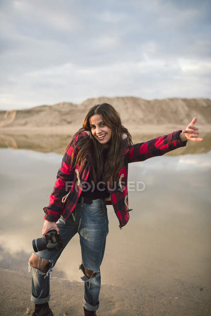 Portrait of laughing young woman with camera on the beach — Stock Photo