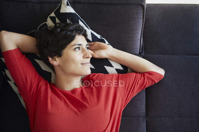 Портрет усміхається жінка, лежачи на канапі в домашніх умовах — стокове фото