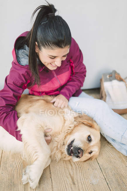 Jovem feliz acariciando e brincando com seu cão golden retriever — Fotografia de Stock