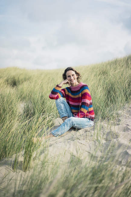 Mulher madura relaxando na praia, sentada nas dunas — Fotografia de Stock