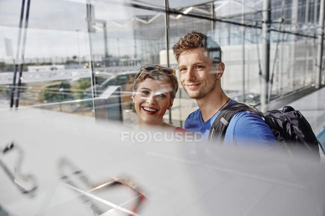 Retrato de pareja sonriente en el aeropuerto mirando por la ventana - foto de stock
