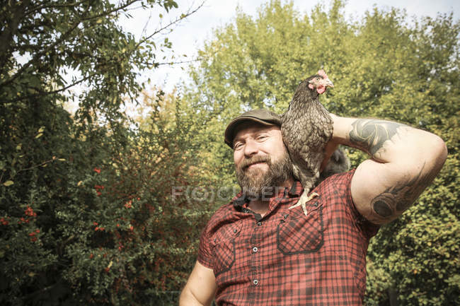 Man in his own garden, man with free range chicken on his shoulder — Stock Photo