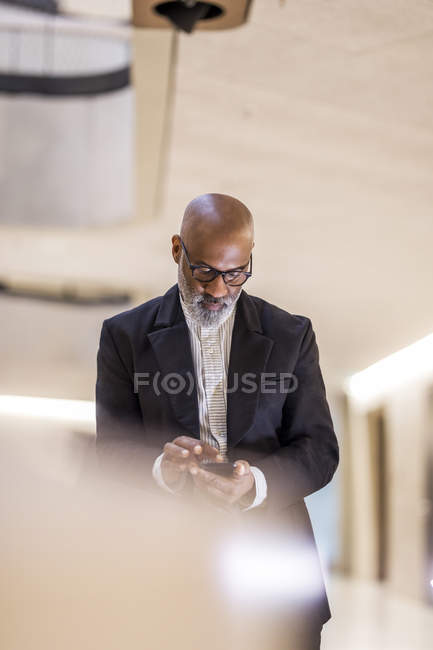 Glatzköpfiger Geschäftsmann mit grauem Handy — Stockfoto