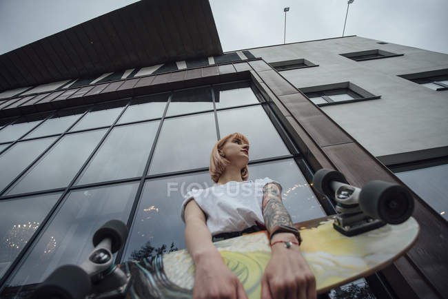 Junge Frau mit Carver-Skateboard vor einem Gebäude — Stockfoto