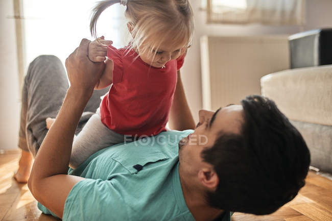 Маленькая девочка играет со своим отцом дома — стоковое фото