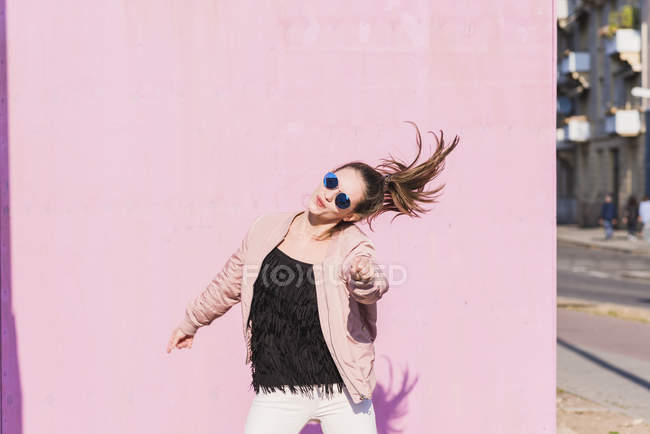 Felice giovane donna che si muove davanti al muro rosa — Foto stock