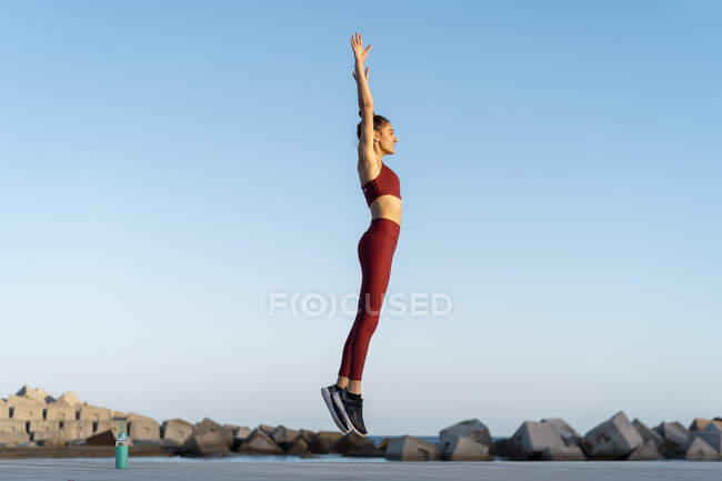 Giovane donna sportiva durante l'allenamento, saltando — Foto stock