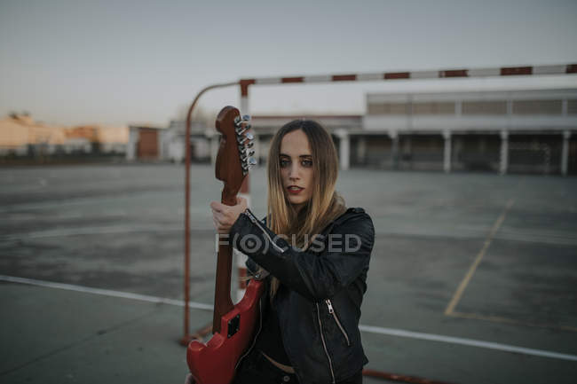 Портрет классной молодой женщины с гитарой на спортивном поле — стоковое фото