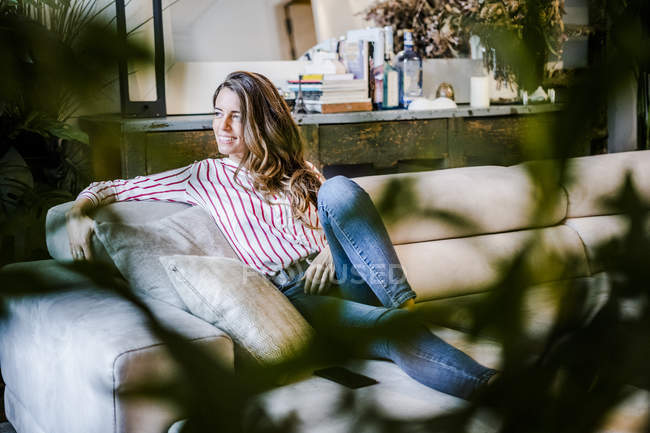 Souriant femme détendue assise sur le canapé — Photo de stock