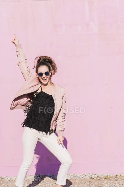 Felice giovane donna gesticolando davanti al muro rosa — Foto stock